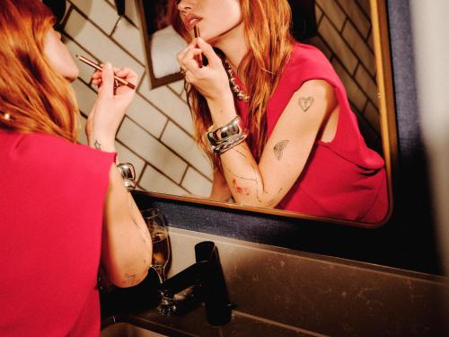 a woman brushing her teeth in front of a mirror at NYX Hotel Edinburgh in Edinburgh