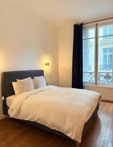 une chambre avec un grand lit blanc avec une fenêtre dans l'établissement Central Champs Élysée - High Luxury 2 Bedroom Apartment, à Paris
