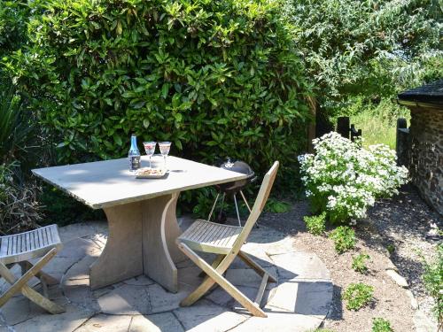 a table with two chairs and a bottle and glasses at The Old Wash House in Pentewan