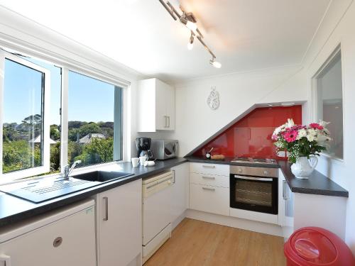 a kitchen with white cabinets and a sink and a window at Florizel in Falmouth