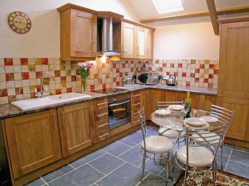 a kitchen with wooden cabinets and a table and chairs at Lower Shippen - 23493 in North Petherwin