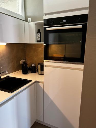 a kitchen with white cabinets and a black microwave at Stylischer Altbau im Zentrum in Kiel