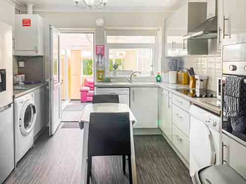 a kitchen with white cabinets and a table in it at The Bay Cottage in Thornton