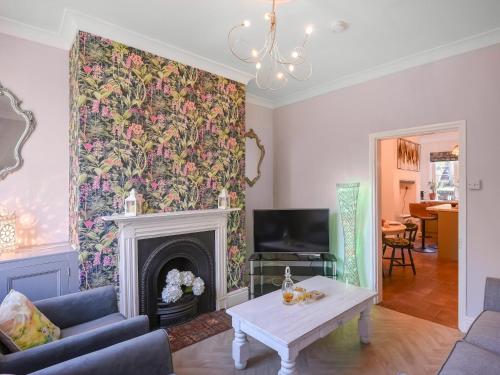 a living room with a fireplace with a floral wallpaper at Bliss House in Madeley