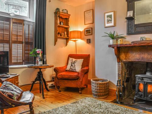 a living room with a chair and a fireplace at Half Pint Cottage in Haworth