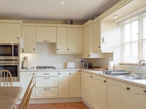 a white kitchen with white cabinets and a sink at Dormers in Leiston