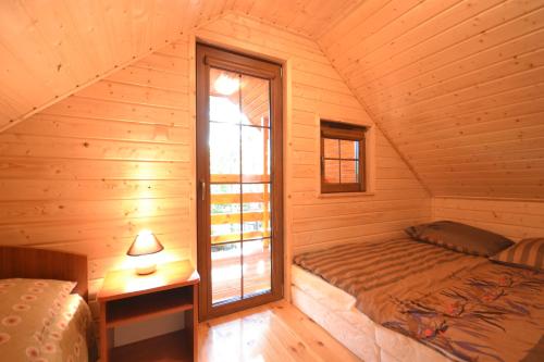 a bedroom with a bed and a window in a log cabin at Mała Frajda in Pustkowo