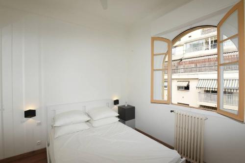 un lit blanc dans une chambre avec une fenêtre dans l'établissement Nice Signature Trachel, à Nice