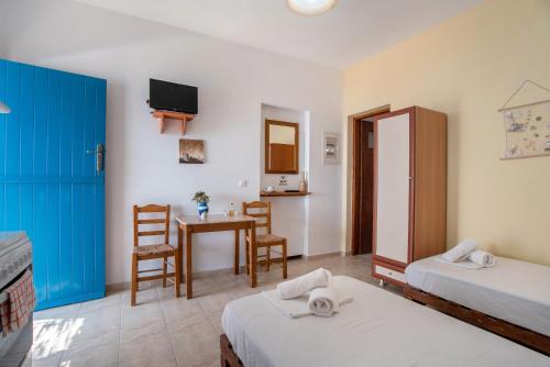 a room with two beds and a table and chairs at Mesaria Studio in Donoussa