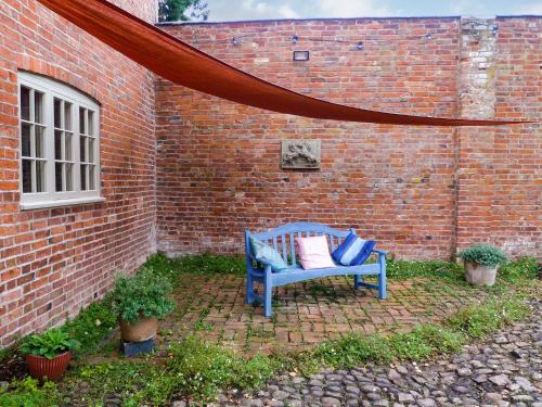 a blue bench sitting next to a brick wall at The Coach House in Syston