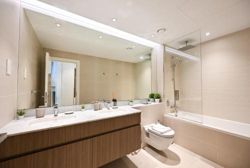 a bathroom with a toilet and a large mirror at Majestic Port de La mer sea view 2BR in Dubai