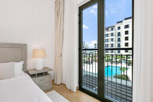 a bedroom with a bed and a balcony with a pool at Majestic Port de La mer sea view 2BR in Dubai