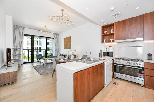 a kitchen with wooden cabinets and a living room at Majestic Port de La mer sea view 2BR in Dubai