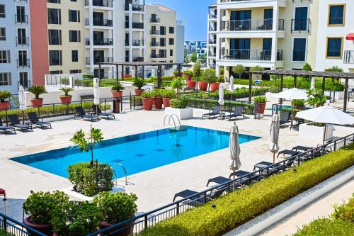 an outdoor pool with chairs and umbrellas at a hotel at Majestic Port de La mer sea view 2BR in Dubai