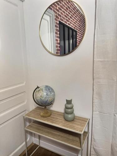un miroir sur un mur au-dessus d'une table avec un vase dans l'établissement Appartement lumineux aux portes de Paris Séjour longue durée idéal Pour Couple & Professionnels, à Malakoff
