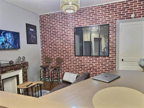 - un salon avec une table et un mur en briques dans l'établissement Appartement lumineux aux portes de Paris Séjour longue durée idéal Pour Couple & Professionnels, à Malakoff