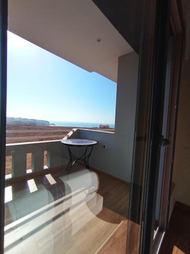 a balcony with a table in front of a large window at Mirleft Horizon Suites in Mirleft