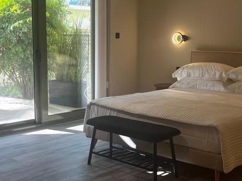a bedroom with a bed and a chair next to a window at Χenion Inn - Athens Airport, Easy Check In Anytime in Markopoulo