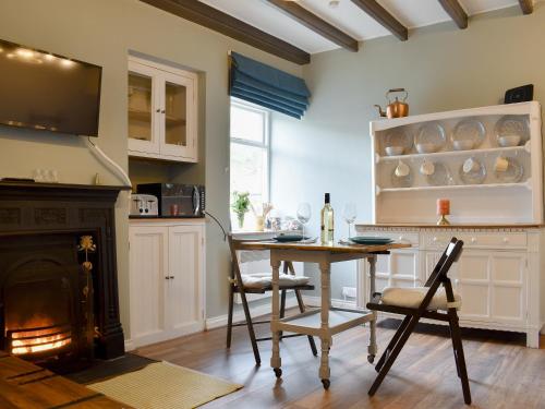 eine Küche mit Tisch und Stühlen und einem Kamin in der Unterkunft Beck View Cottage in Staithes