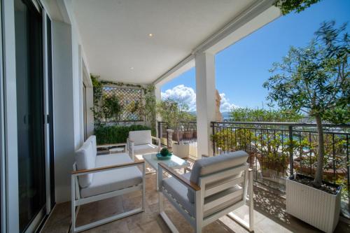 a patio with white chairs and a table on a balcony at Lustica Bay Marina Village by 2BHome in Lustica
