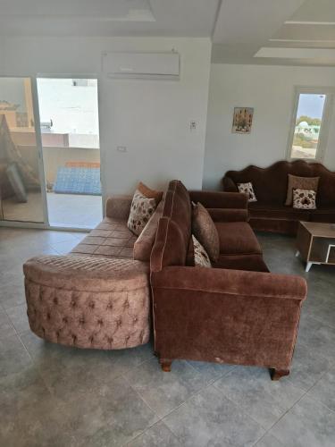 a living room with a couch and a ottoman at Dar Marhaba bis karkouane in Kerkouene