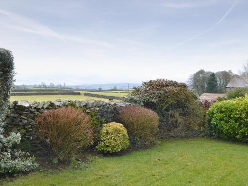 a garden with a stone wall and bushes at Ribblestones in Austwick