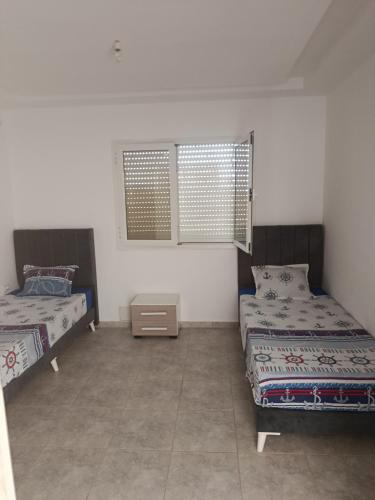 a room with two beds and a table and two windows at Dar Marhaba bis karkouane in Kerkouene