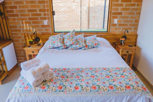 a bedroom with a bed with towels on it at Pousada Ho'oponopono Chalets & Wine in Sapucaí-Mirim