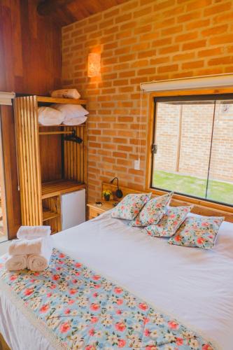 a bed in a room with a brick wall at Pousada Ho'oponopono Chalets & Wine in Sapucaí-Mirim