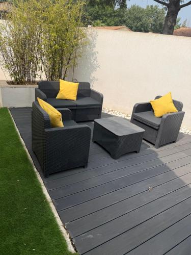 trois chaises en osier avec des coussins jaunes sur une terrasse dans l'établissement Maison avec jardin à 8 min de l'aéroport, à Saint-Victoret