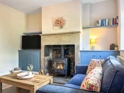 a living room with a blue couch and a fireplace at Alders Cottage in Tansley
