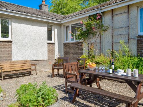 a patio with a wooden table and benches at Dunyvaig in Colintraive