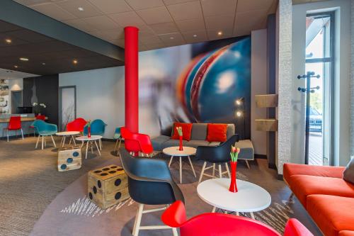 a waiting room with red and blue chairs and tables at Ibis Częstochowa in Częstochowa