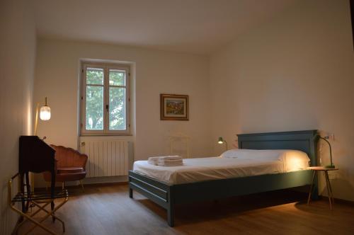 Un dormitorio con una cama y una silla y una ventana. en Casale Pura Vita, en Castiglion Fiorentino