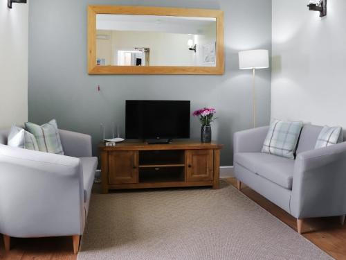 ein Wohnzimmer mit einem TV und 2 Stühlen in der Unterkunft Rhiw Farmhouse in Llangelynin