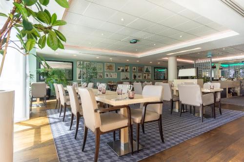 une salle à manger avec des tables et des chaises blanches dans l'établissement City Résidence Paris CDG Airport, à Roissy-en-France