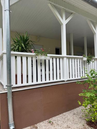 a porch with a white railing and potted plants at Szem-s Vendégház in Balatonszemes