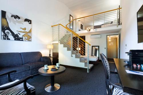 a living room with a couch and a staircase at SOWELL HOTELS Domaine de la Petite Isle in LʼIsle-sur-la-Sorgue