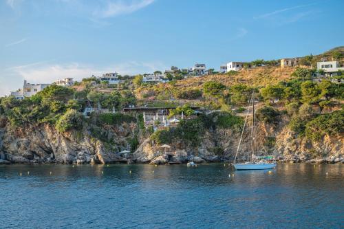 a boat sitting in the water next to a cliff at Azure Horizon Skyros in Skiros