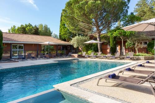 a swimming pool with lounge chairs and an umbrella at SOWELL HOTELS Domaine de la Petite Isle in LʼIsle-sur-la-Sorgue