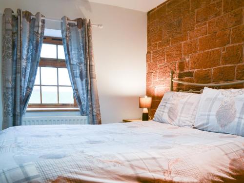 a bedroom with a bed and a brick wall at Meadow Lodge-E4105 in Aspatria