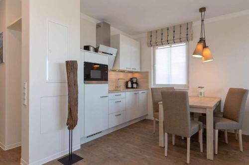a kitchen and dining room with a table and a refrigerator at Aparthotel Waterkant Suites - Fewos am Meer mit SPA in Börgerende-Rethwisch