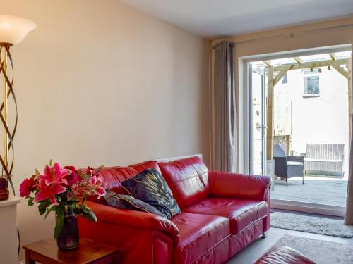 a red leather couch in a living room with a window at Morwood Cottage in Porthcawl