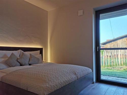 a bedroom with a bed and a large window at Neues stilvolles Ferienhaus Südsteiermark in ruhiger Lage top Aussicht inkl Wallbox in Eibiswald