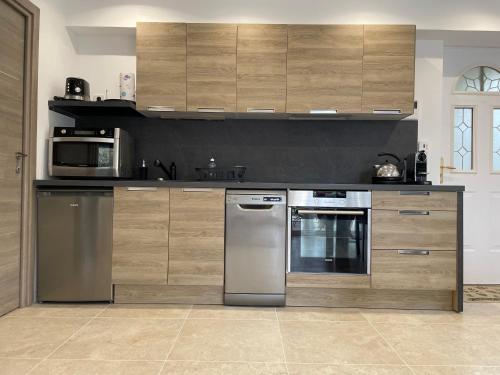 une cuisine avec des appareils en acier inoxydable et des armoires en bois dans l'établissement Appartement 4 personnes avec jacuzzi au calme, à Carros