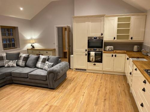 a living room with a couch and a kitchen at Pointer Cottage in Preesall