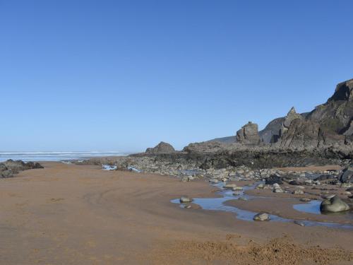 a beach with rocks and water on the sand at Hillside in Kilkhampton