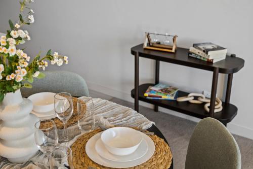 a dining room table with plates and a vase of flowers at Stunning Lake-View in Belconnen in Belconnen