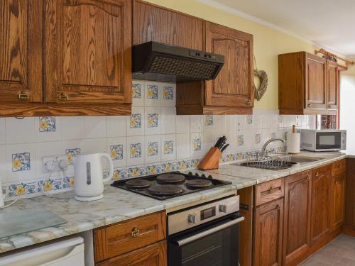 a kitchen with wooden cabinets and a stove top oven at Leys Barn in Great Chishall