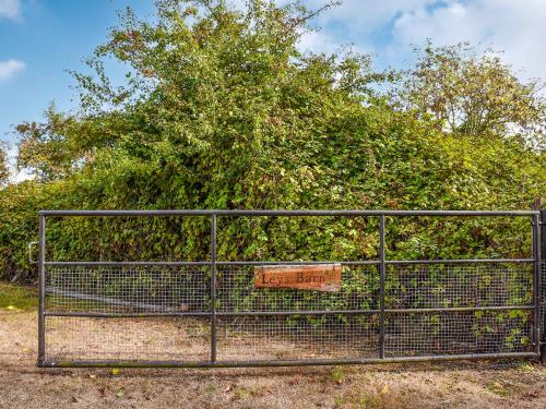 a fence with a sign on it in front of a bush at Leys Barn in Great Chishall